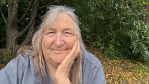 Frau mit Hand am Kinn vor Büschen